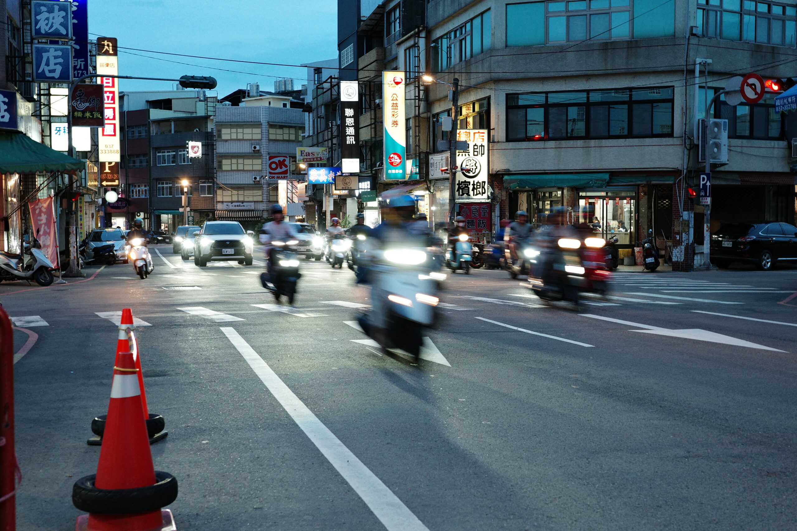 Busy intersection with motorcycles under city lights at night.