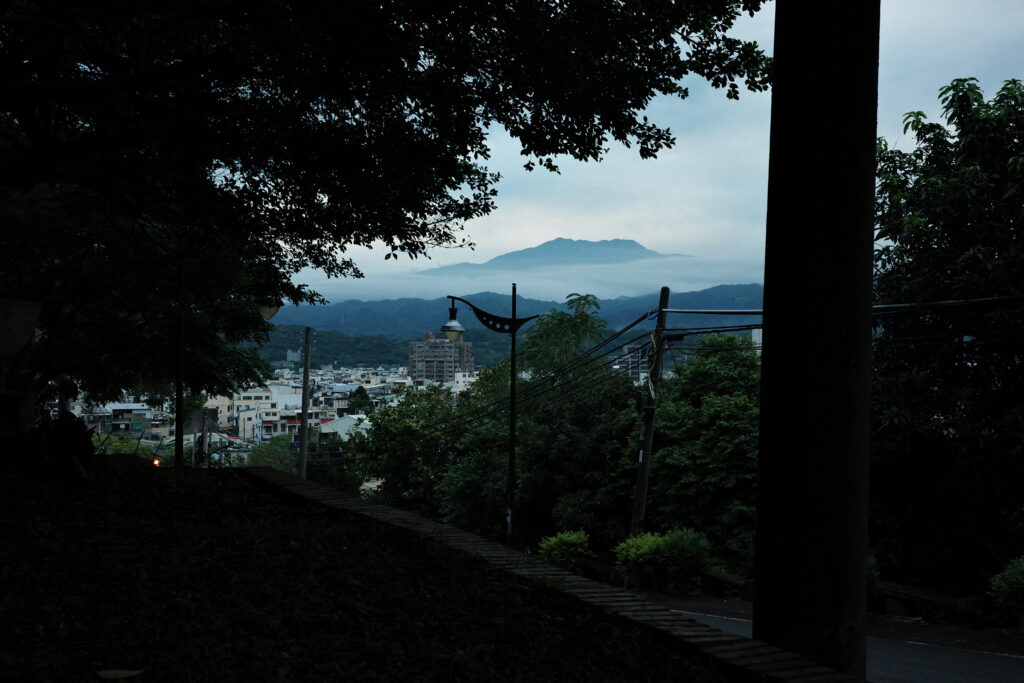 Blue dusk view of a quiet town transitioning into night, soft light over rooftops.