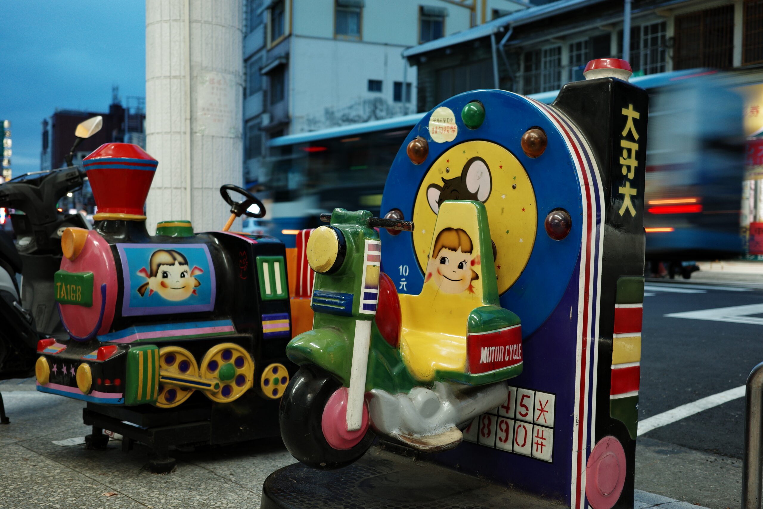 Children's coin-operated ride glowing faintly on a quiet street.