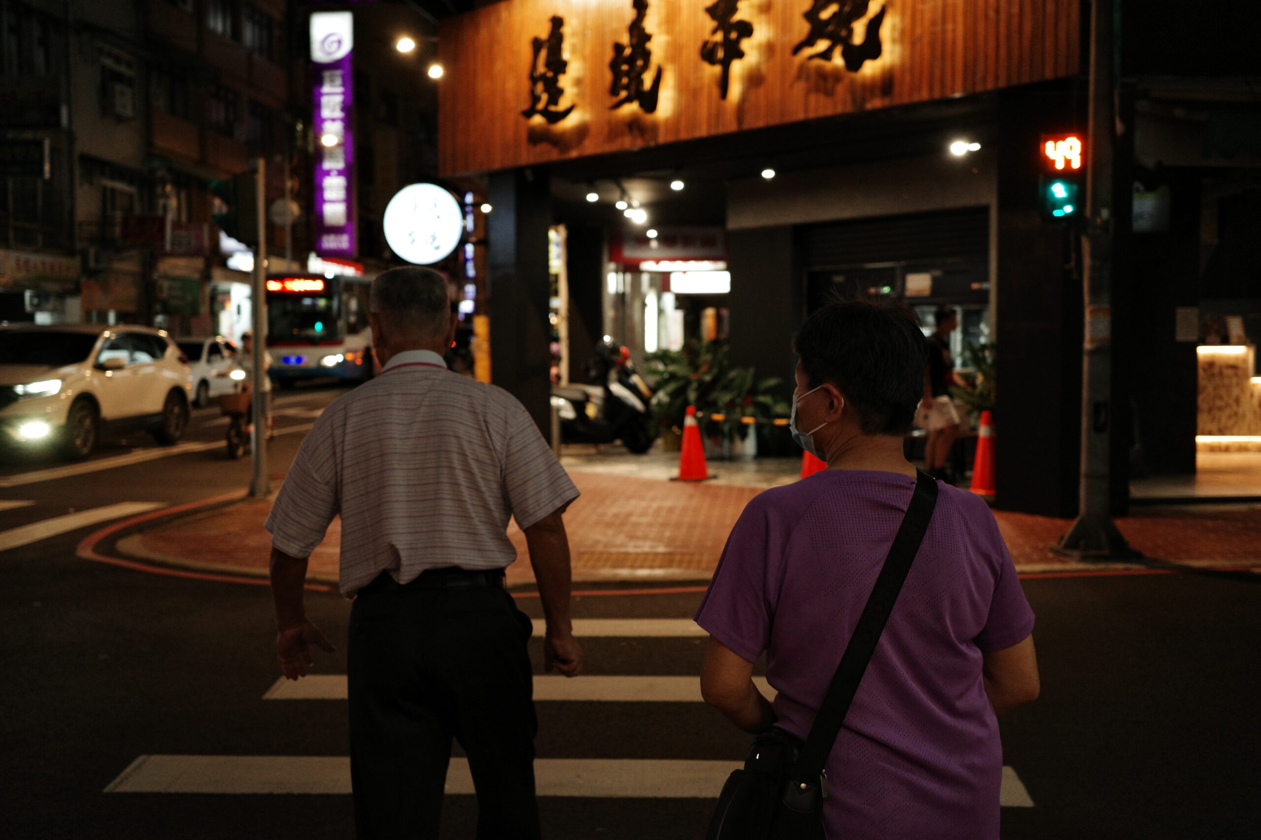 Two people walking under streetlights at night, soft glow on the pavement.