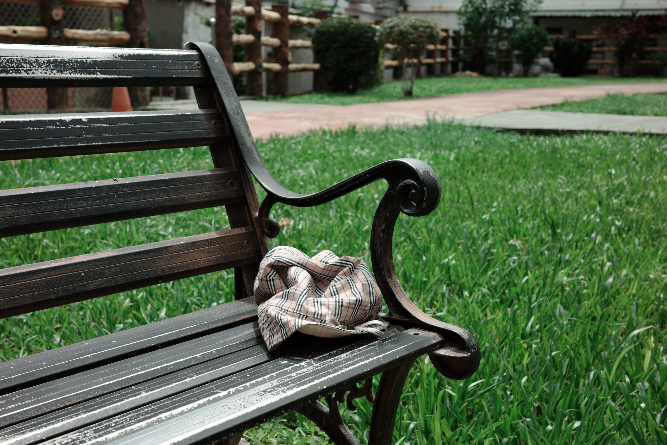 Weathered wooden bench with a folded cloth bag on it, beside a field of green grass – Scentography style
綠草旁的斑駁木椅，上面放著摺好的布包 —— 氣韻攝記風格